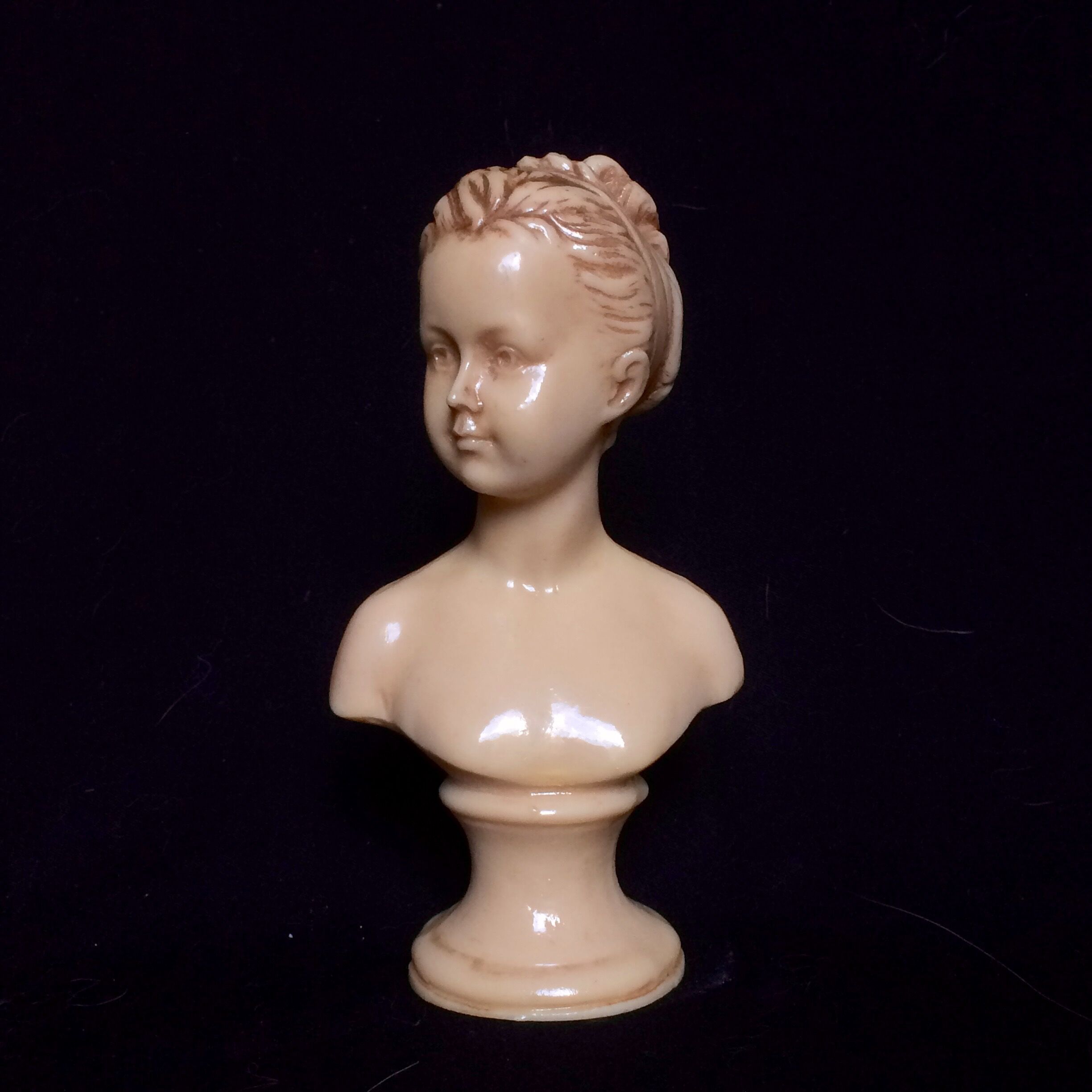 Bust in varnished dish, young girl with bun