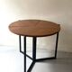 Modernist round folding dining table in wood and metal.