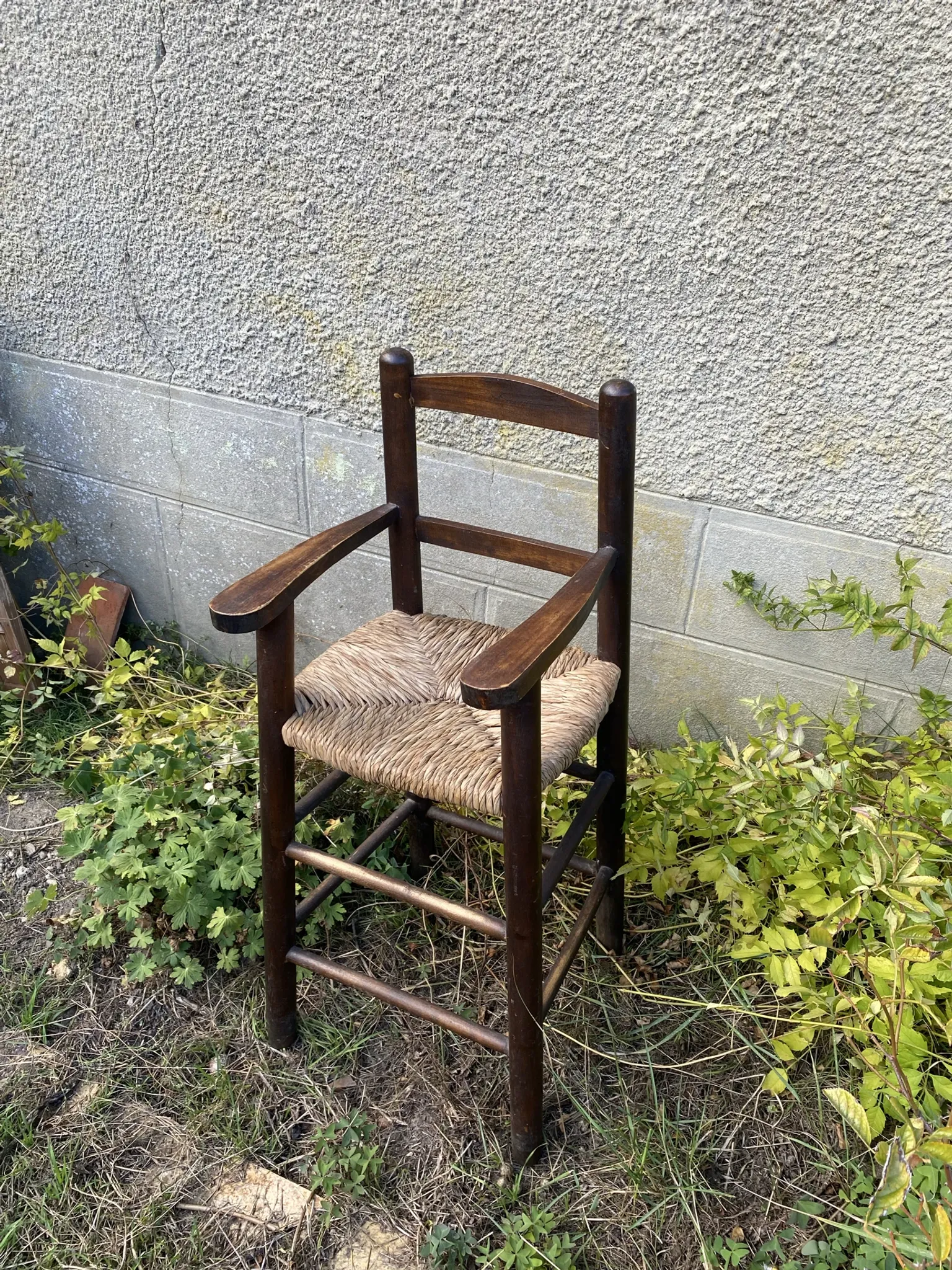 Vintage wooden children's high chair with straw.