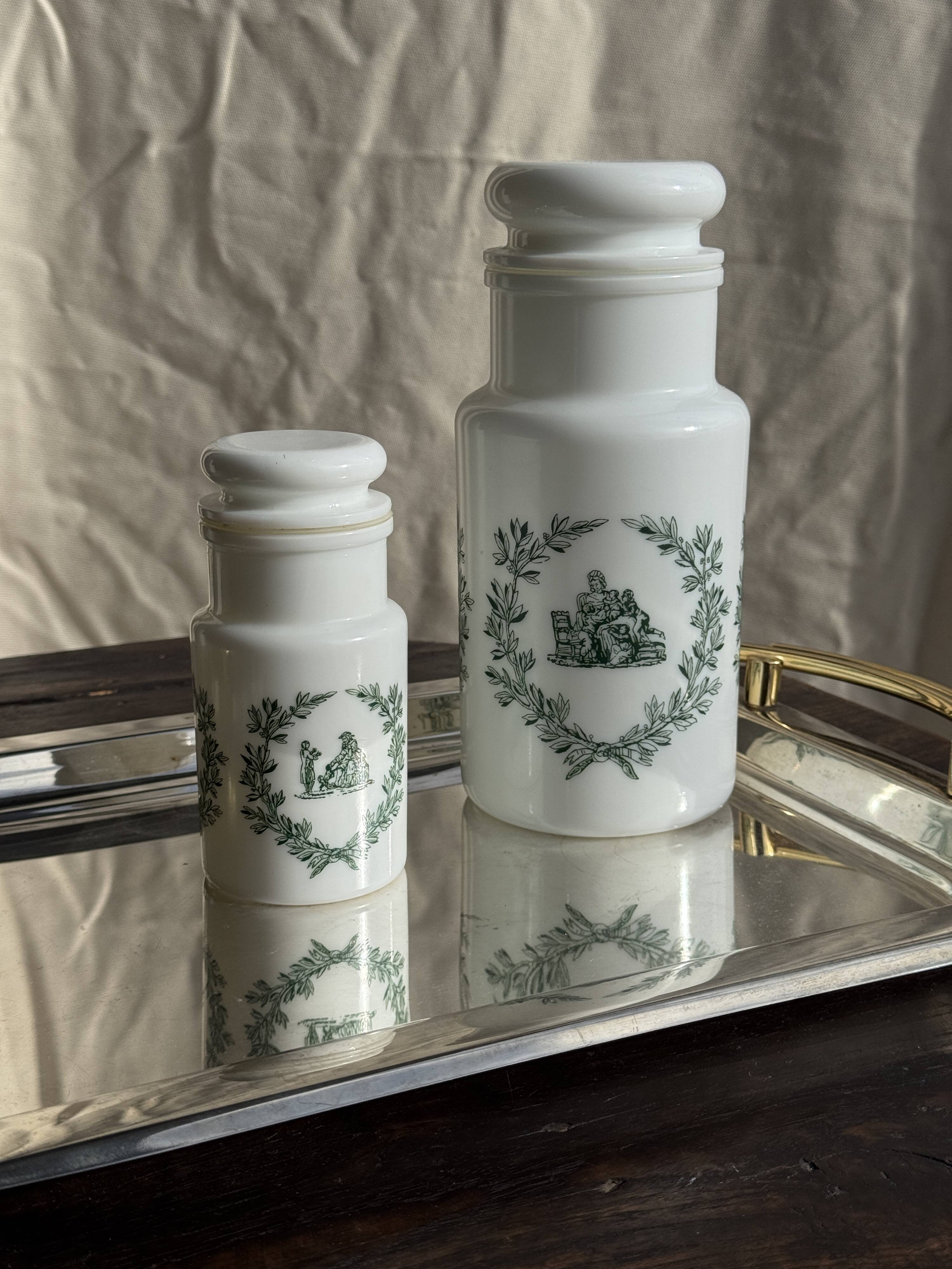 A pair of white glass bottles with Italian green patterns.