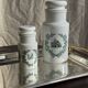 A pair of white glass bottles with Italian green patterns.
