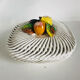 Covered basket in white woven ceramic and fruit slip.