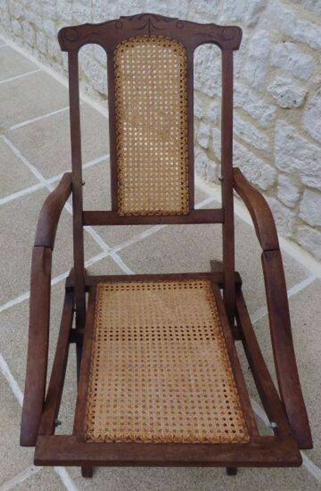 Antique folding chair with caned seat and backrest made of wood.