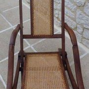 Antique folding chair with caned seat and backrest made of wood.