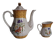 Golden porcelain teapot and coffee pot set with floral design and matching milk jug.