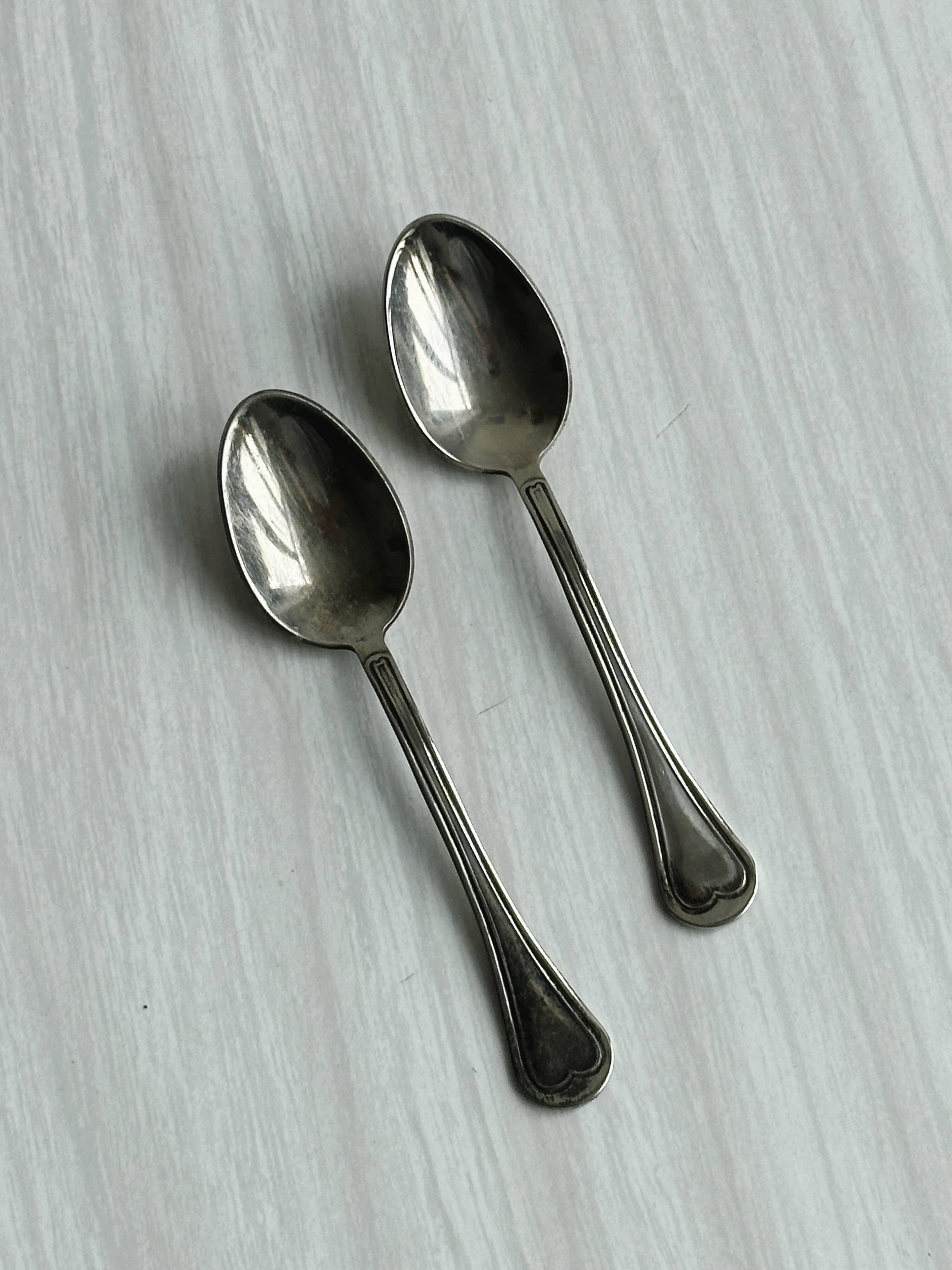 2 porcelain cups with metal supports and small spoons.