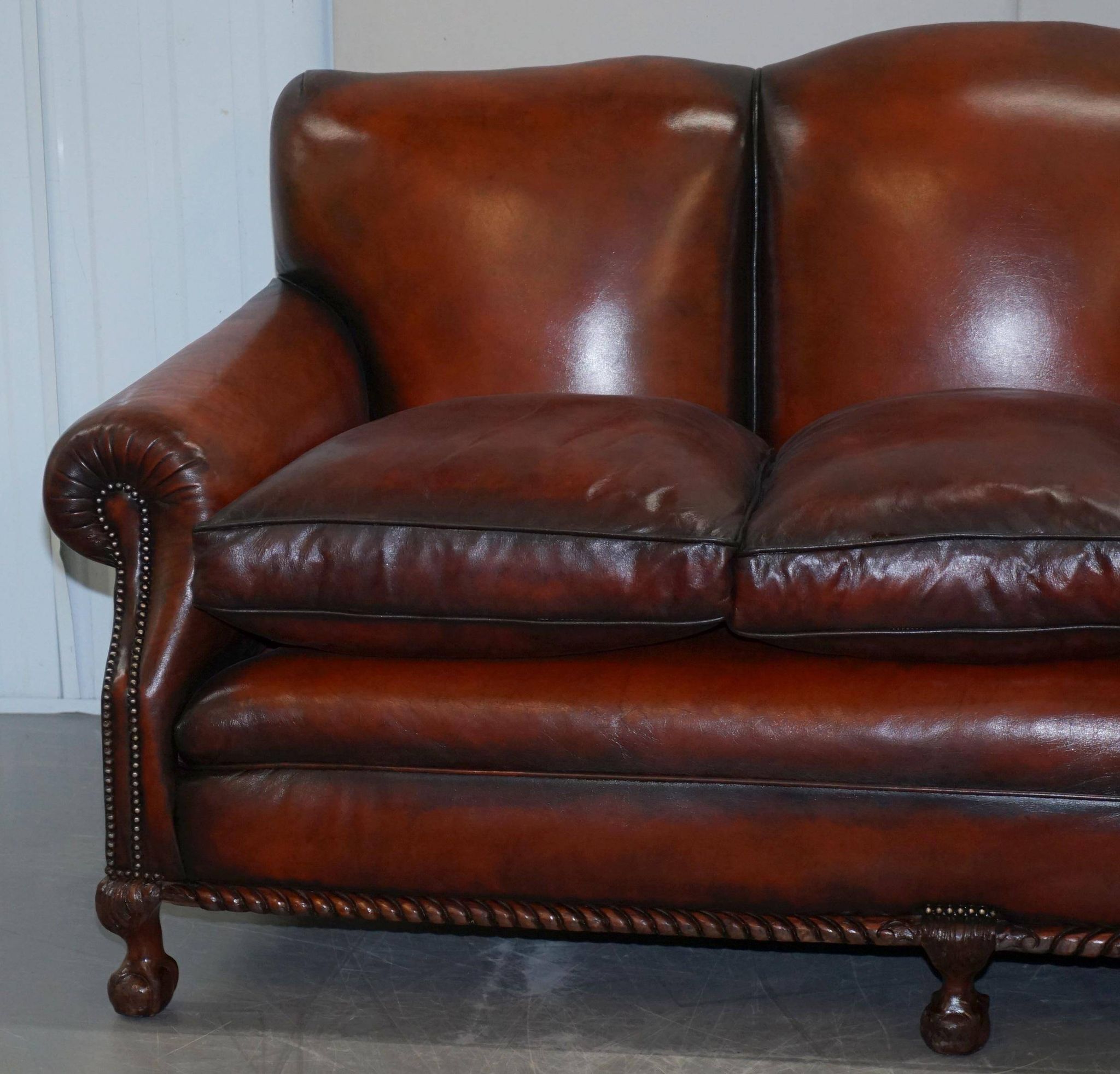 Restored Victorian sofa in leather with claw feet and feather cushions.