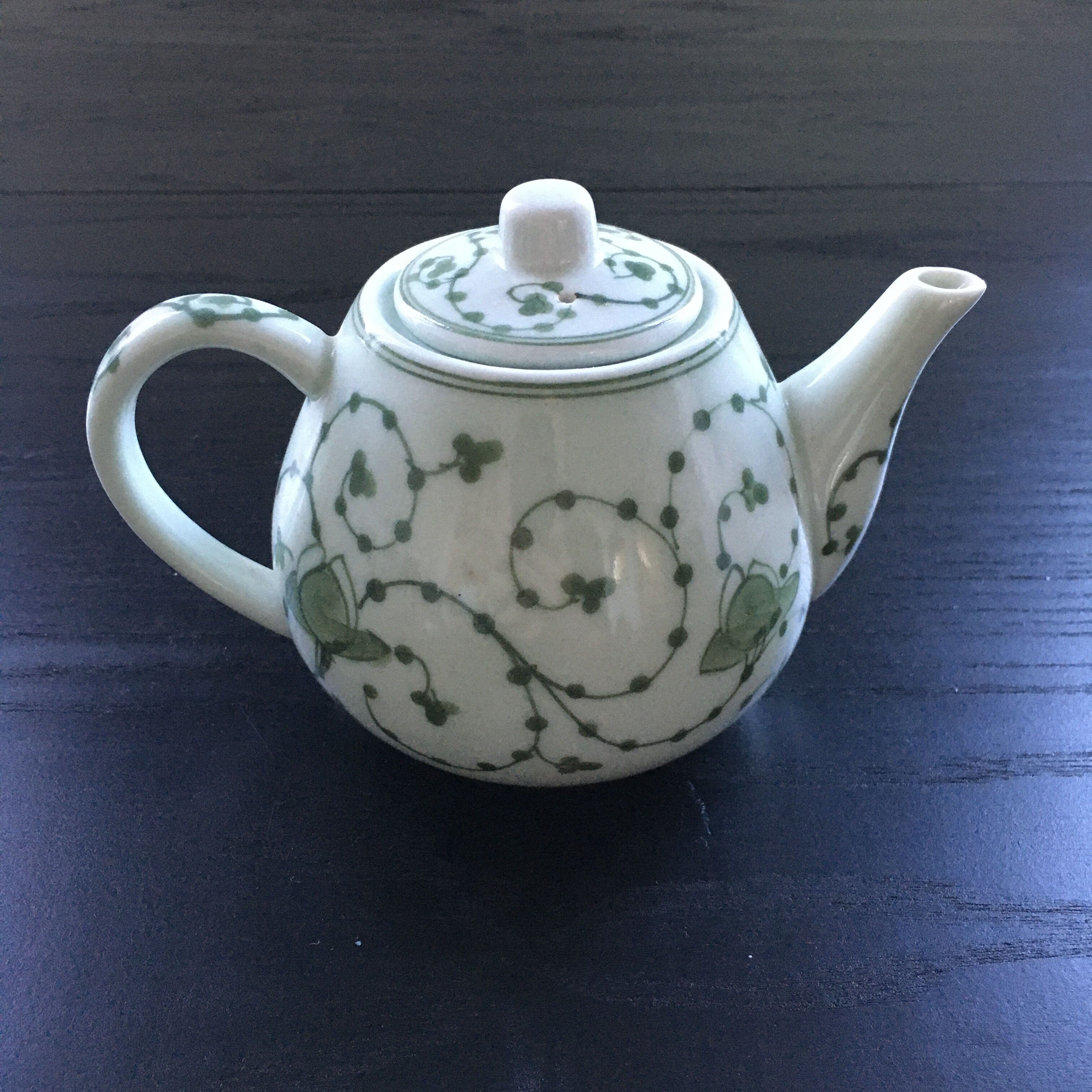 Green plant-decorated teapot