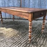 Antique farmhouse table in solid cherry wood with turned legs.