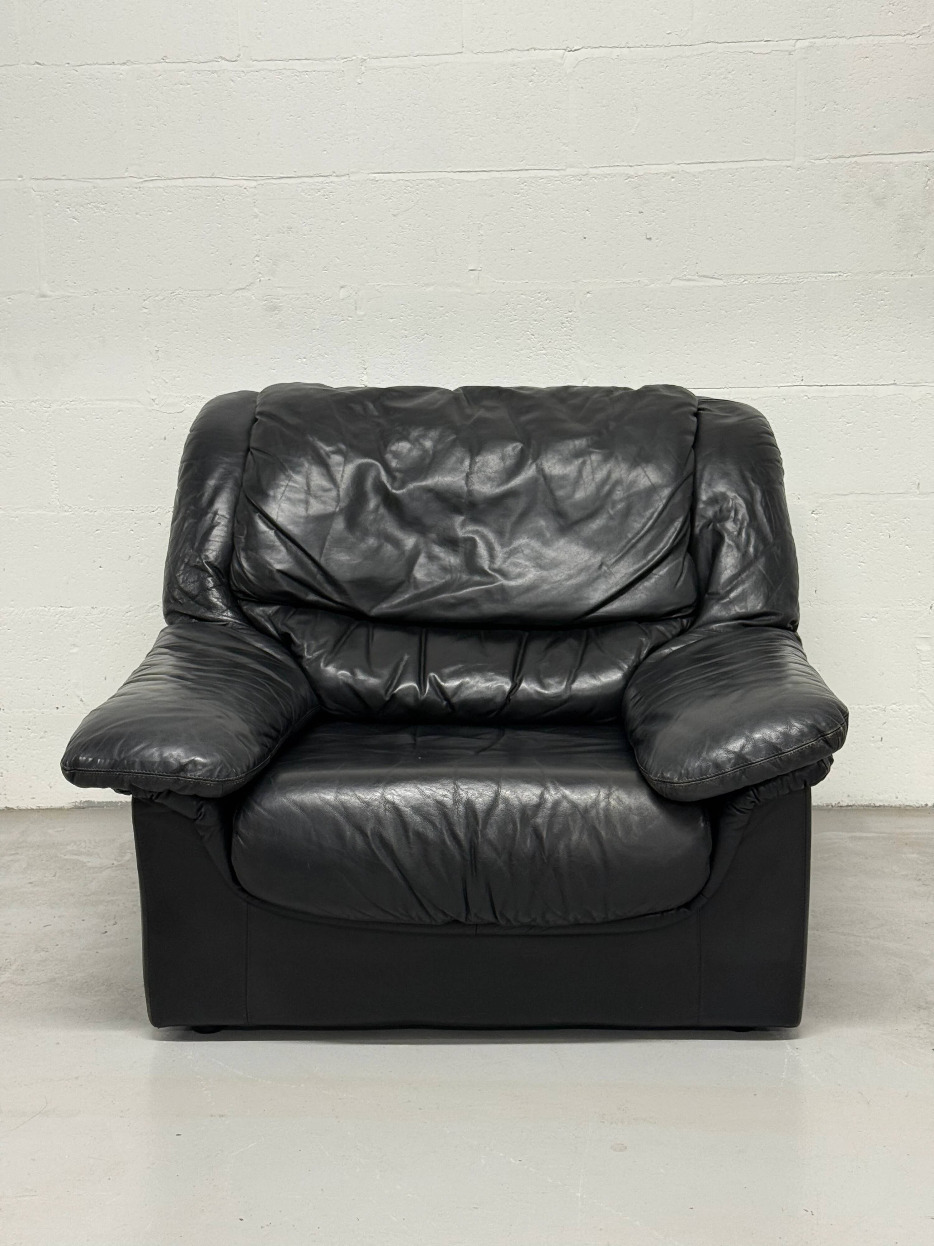 Vintage black leather lounge chair — low postmodern club chair from the space age.