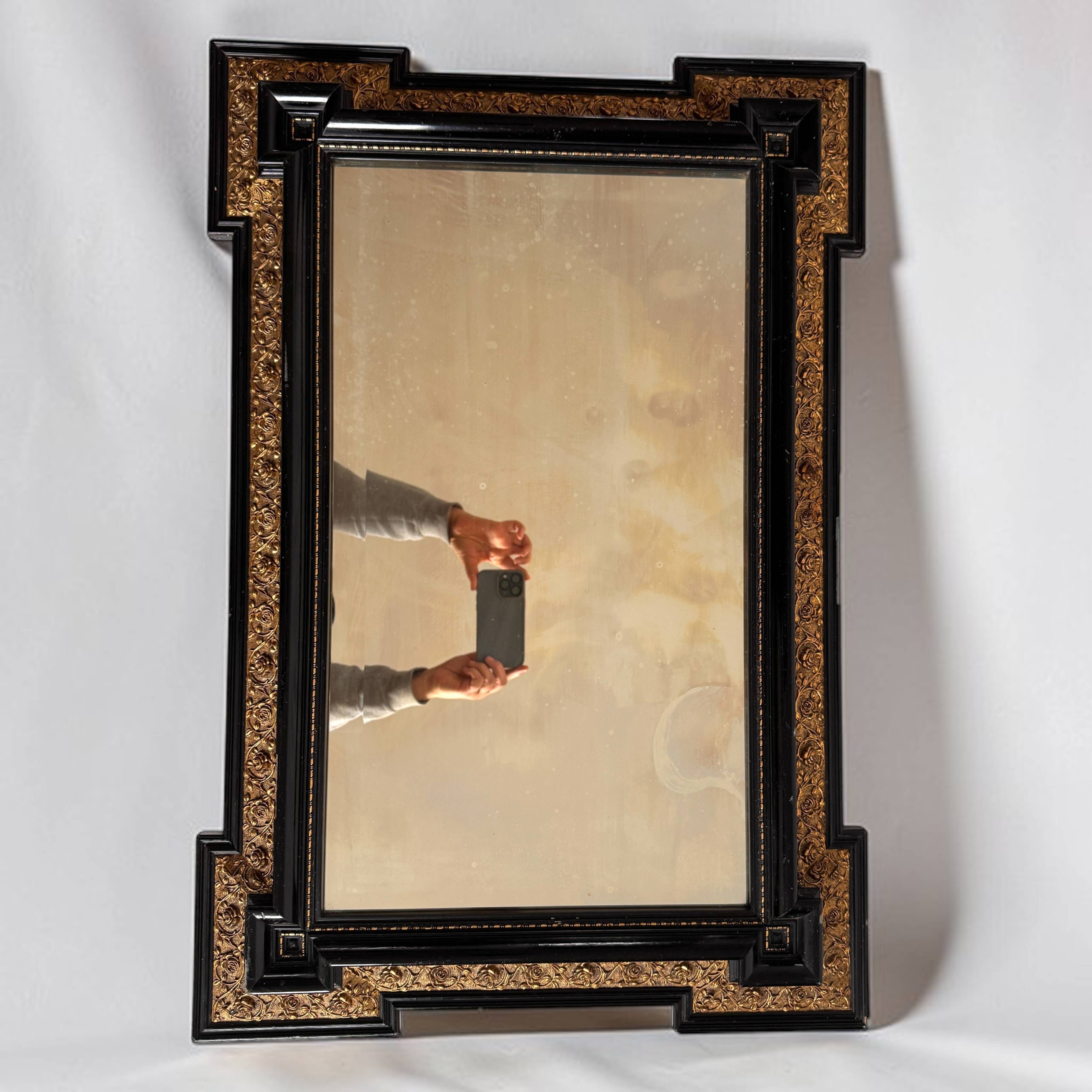 Antique wall mirror in blackened wood and gilded stucco, 19th-century Dutch style.