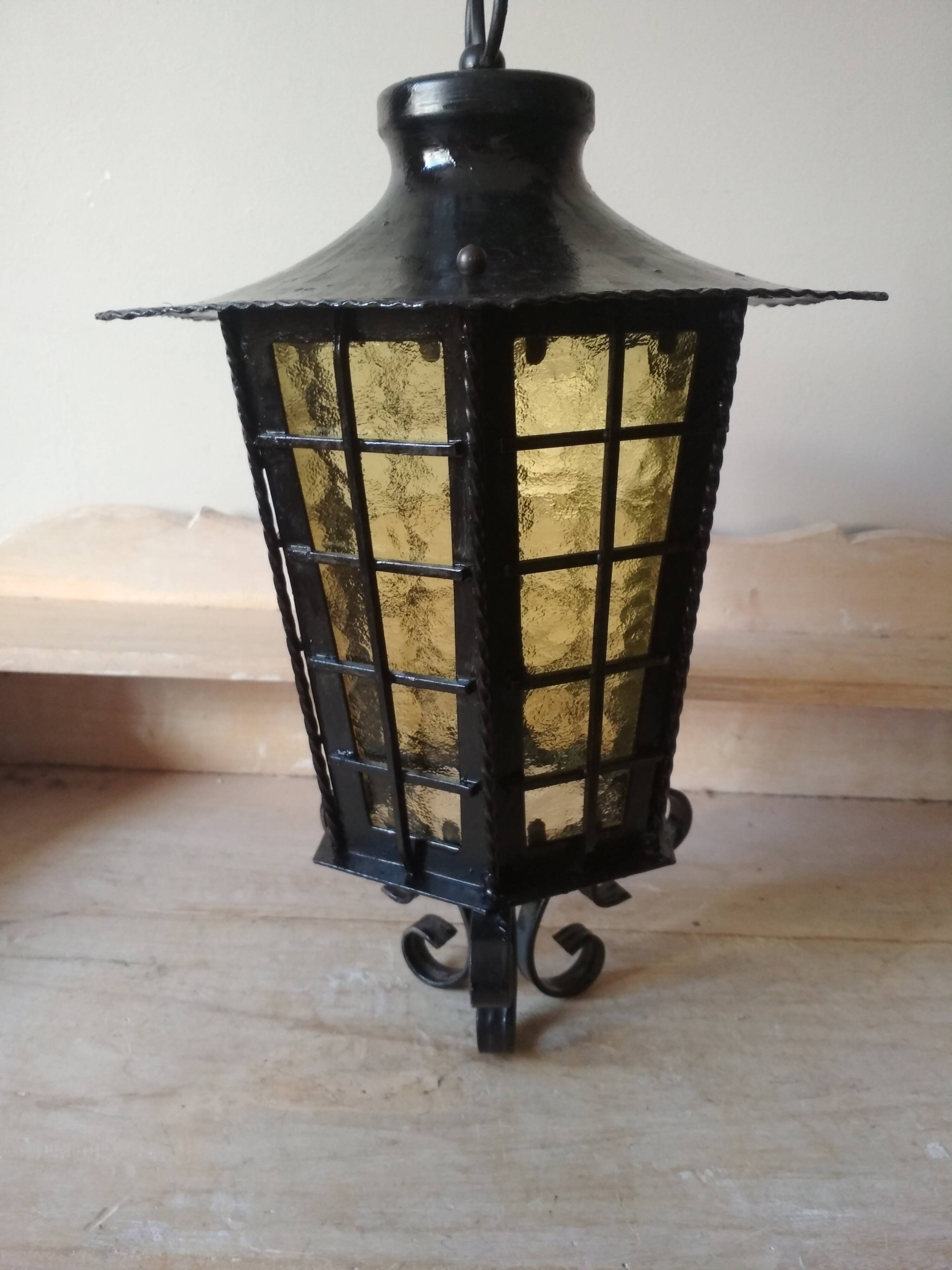 Large hanging lantern in wrought iron and opaque yellow-orange windows
