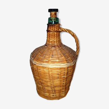 Old bottle in green glass covered with Wicker braided