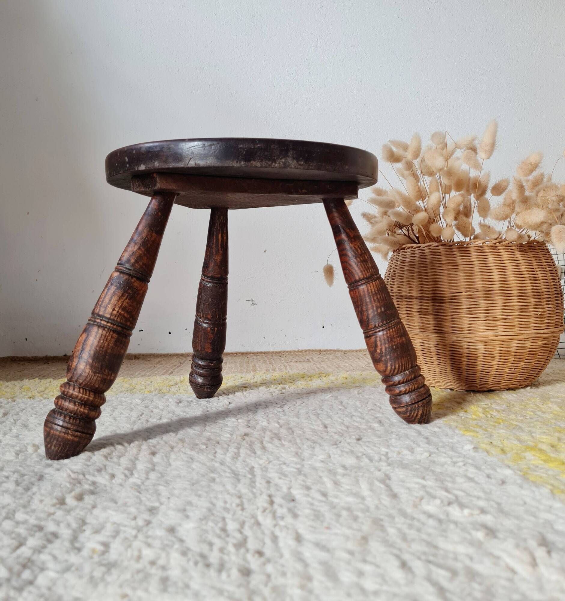Small brutalist tripod stool made of turned wood.