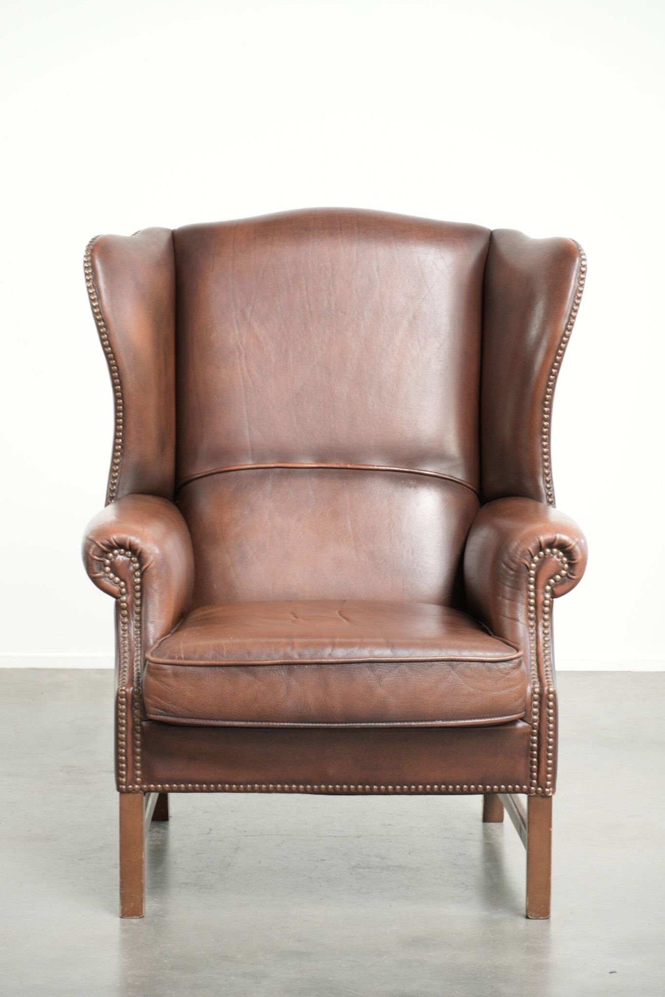 Fauteuil à oreilles en cuir de vache confortable de style anglais avec un look intemporel.