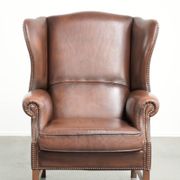 Fauteuil à oreilles en cuir de vache confortable de style anglais avec un look intemporel.