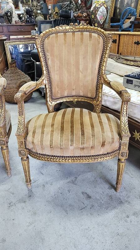 A pair of gilded wooden armchairs in the Louis XVI style.