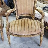 A pair of gilded wooden armchairs in the Louis XVI style.