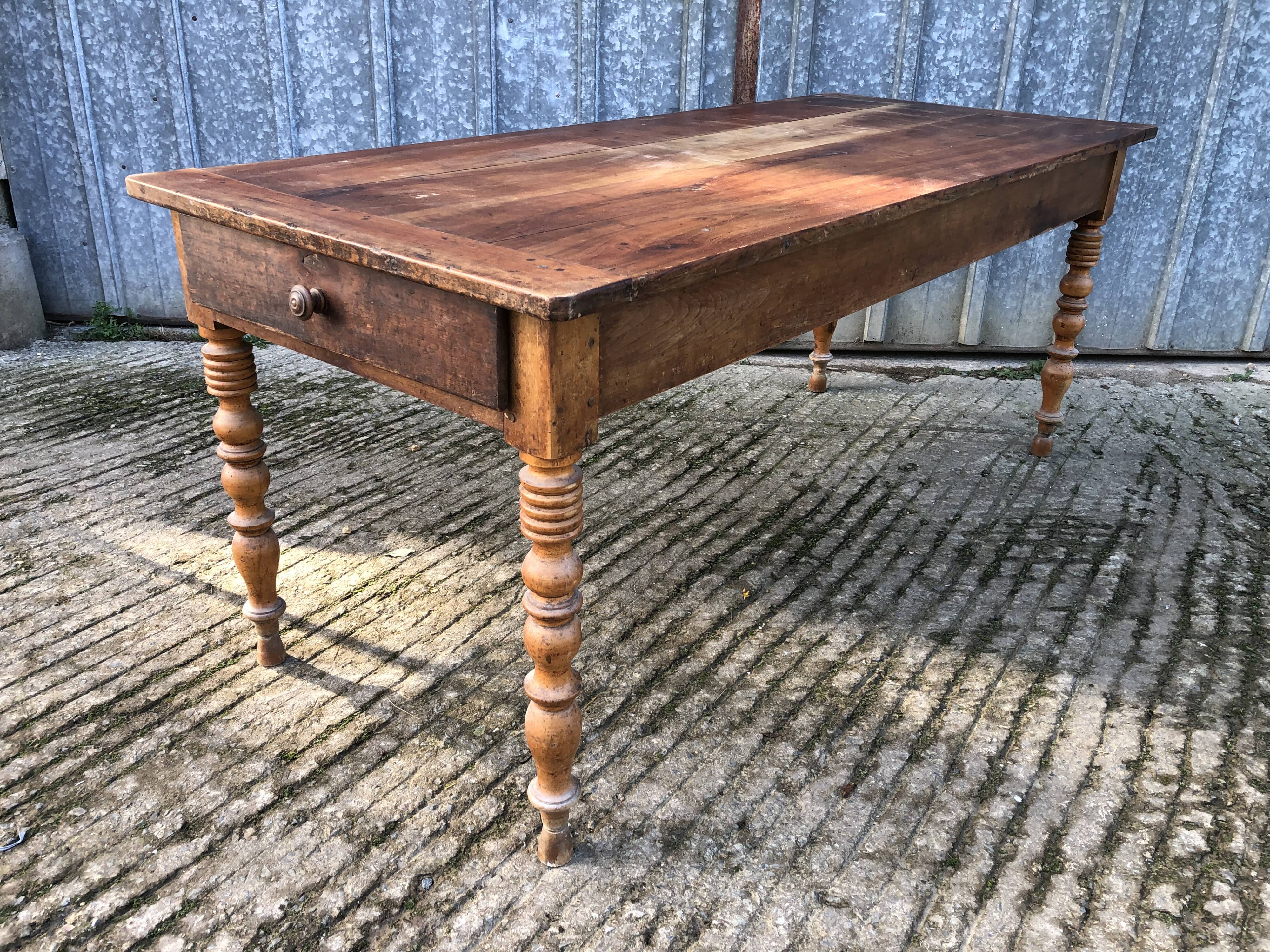 Antique farmhouse table in solid cherry wood with turned legs.