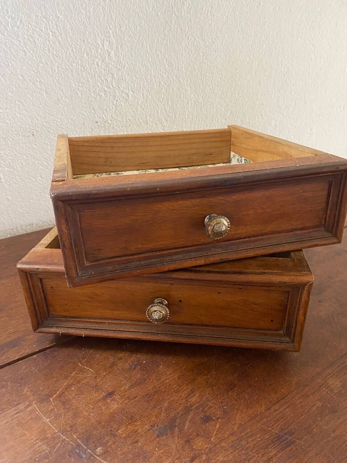 2 tiroirs en bois au bouton en laiton ciselé .