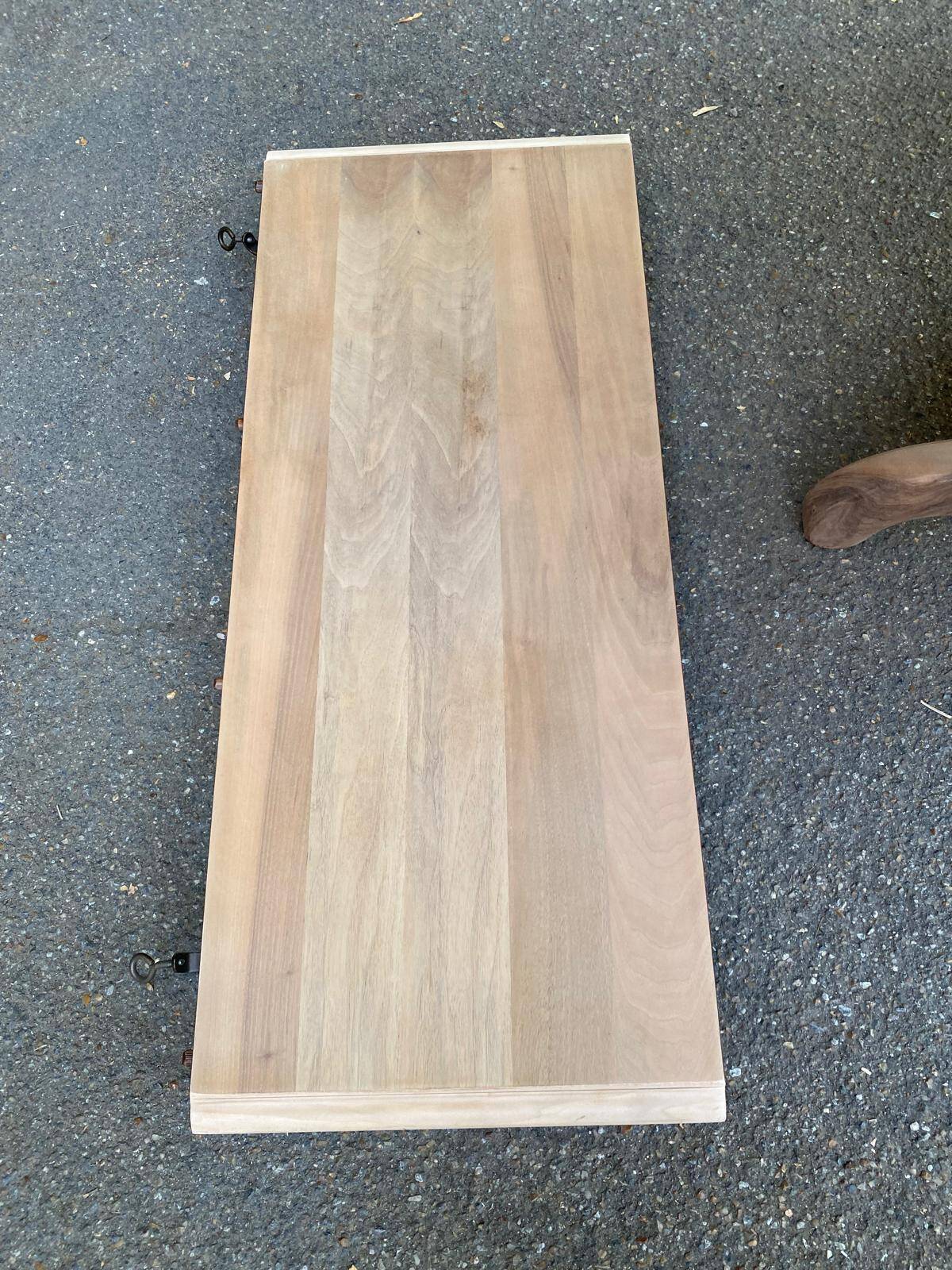 Round extendable dining table stripped in solid raw walnut with a central leg.