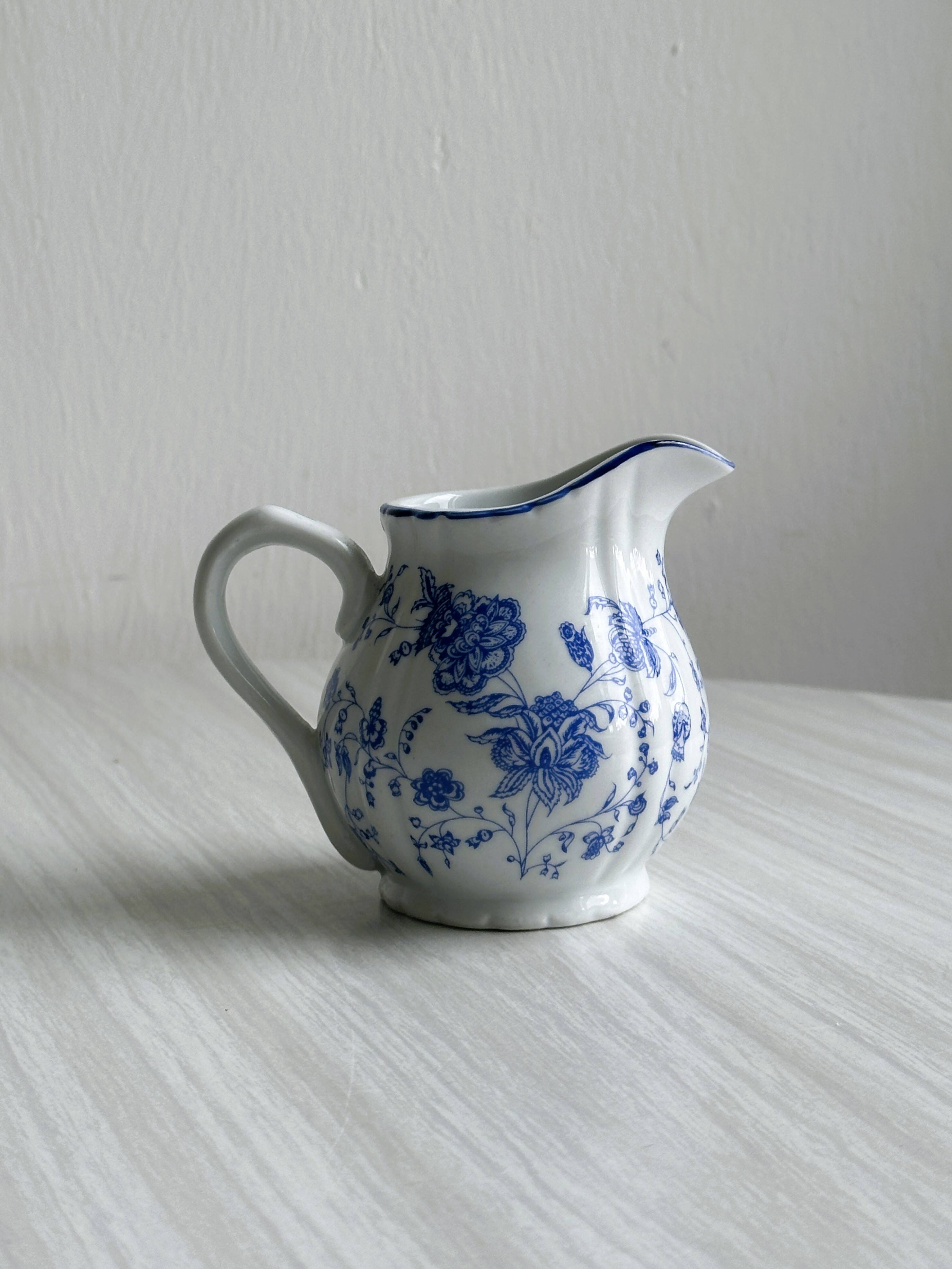 White porcelain milk jug with blue floral designs.
