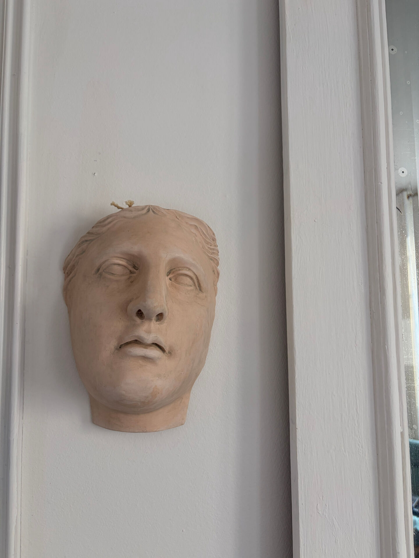 Wall sculpture of the face of the Venus de Milo in plaster.
