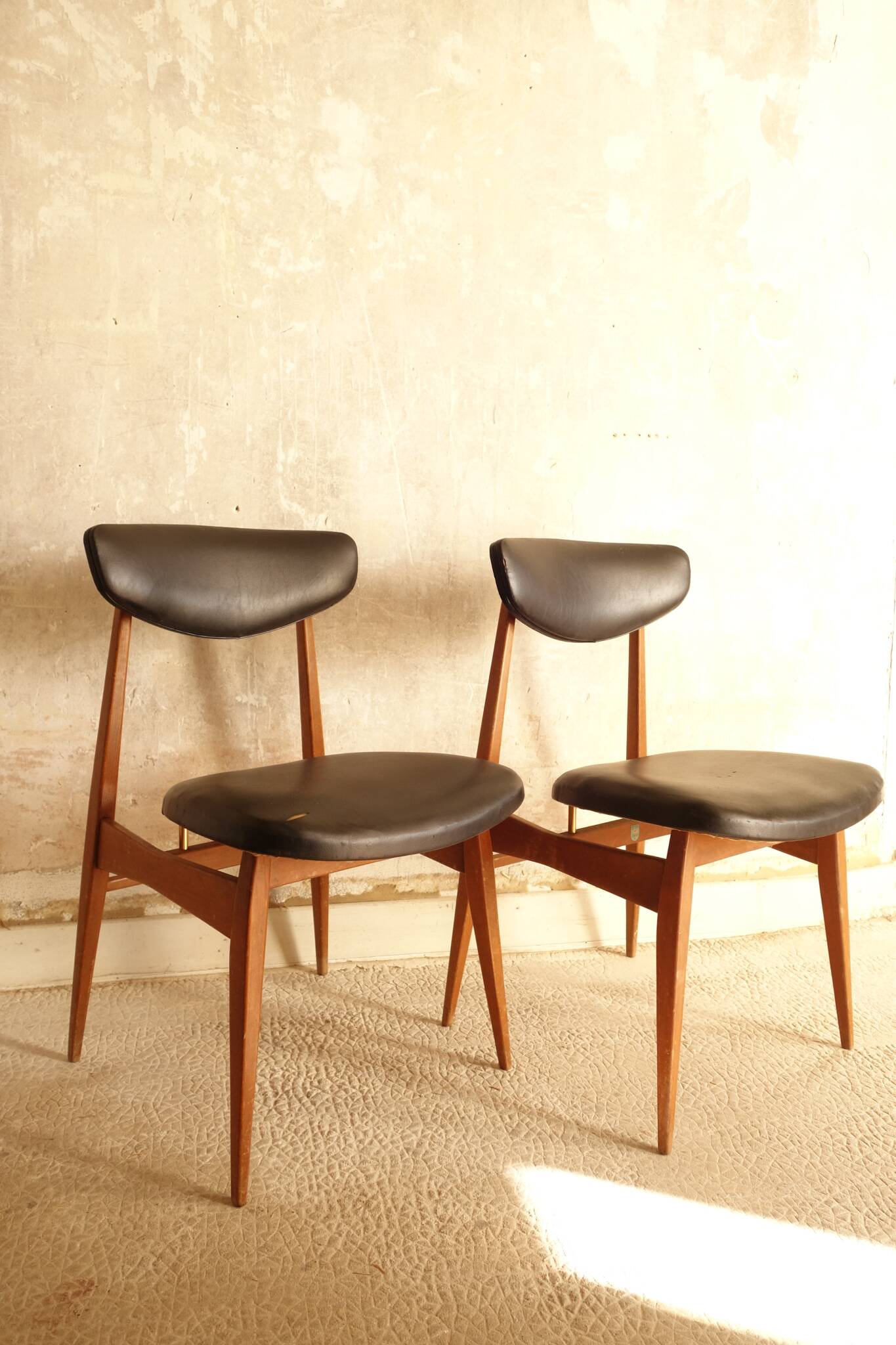 Pair of modernist Scandinavian chairs in teak and black faux leather.