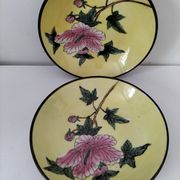 A pair of vintage Chinese decorative plates with floral designs on a yellow background.