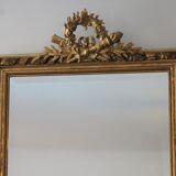 Miroir ancien doré surmonté d'un fronton et glace biseautée