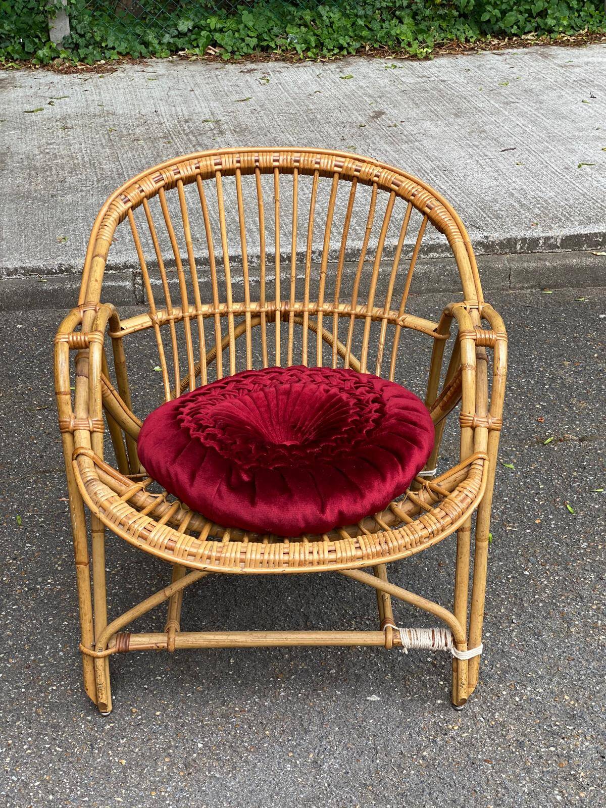 1970s adult rattan and wicker armchair with a round burgundy velvet cushion.