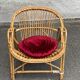 1970s adult rattan and wicker armchair with a round burgundy velvet cushion.