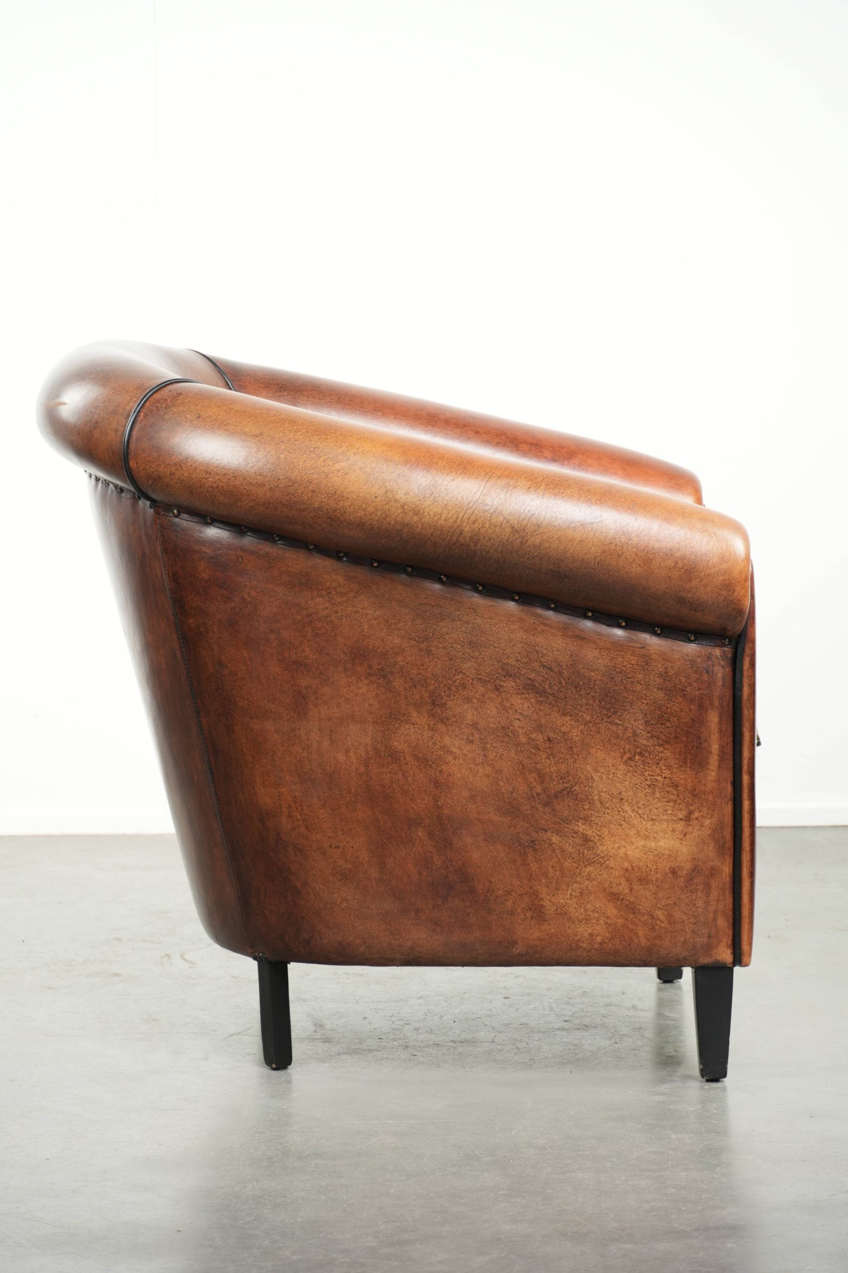 Sheepskin club armchair with deep warm colours and black piping