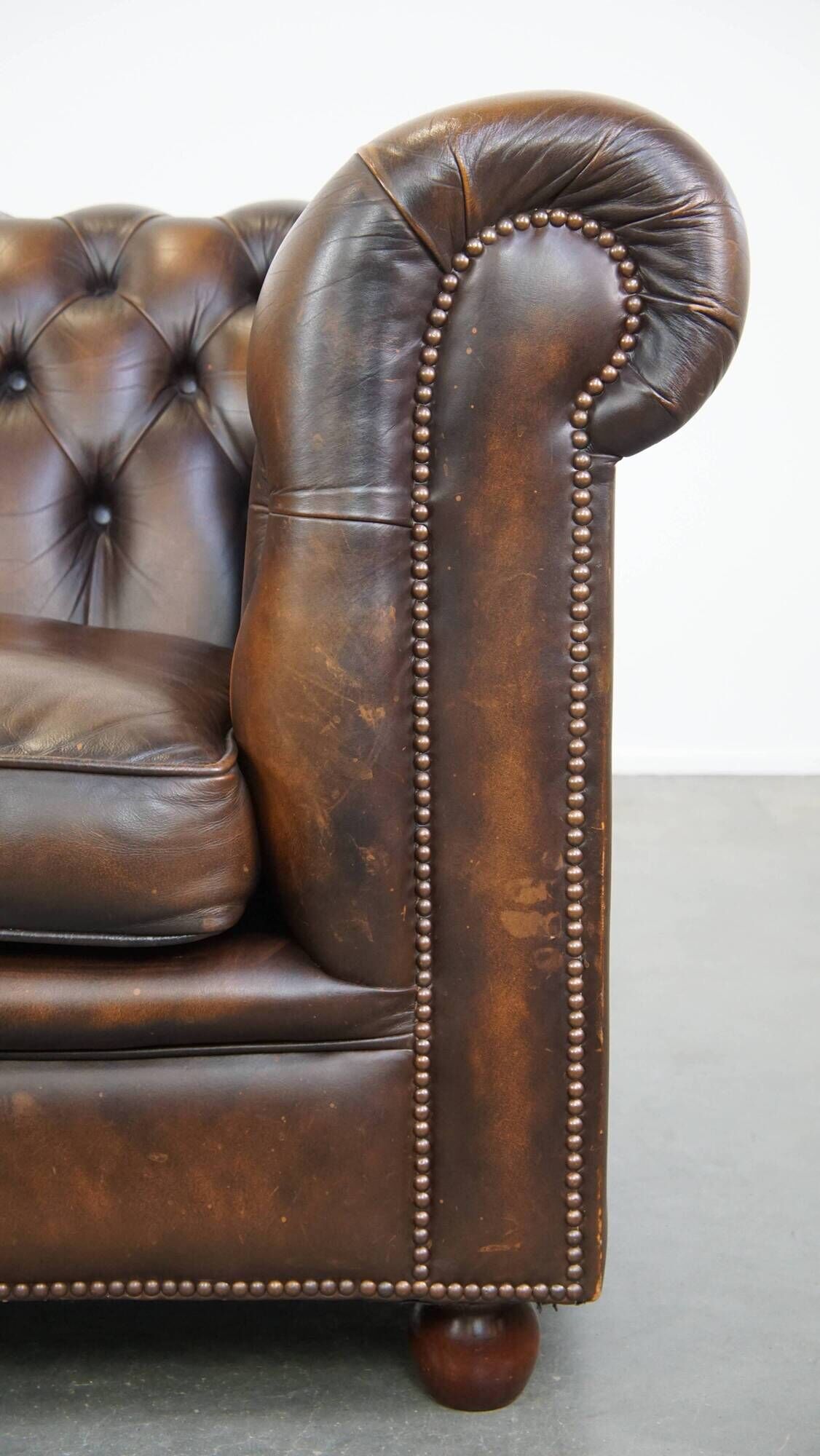 Cowhide English Chesterfield armchair with ball legs and timeless finish