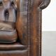 Cowhide English Chesterfield armchair with ball legs and timeless finish