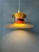 Large UFO flying saucer pendant light with orange light.