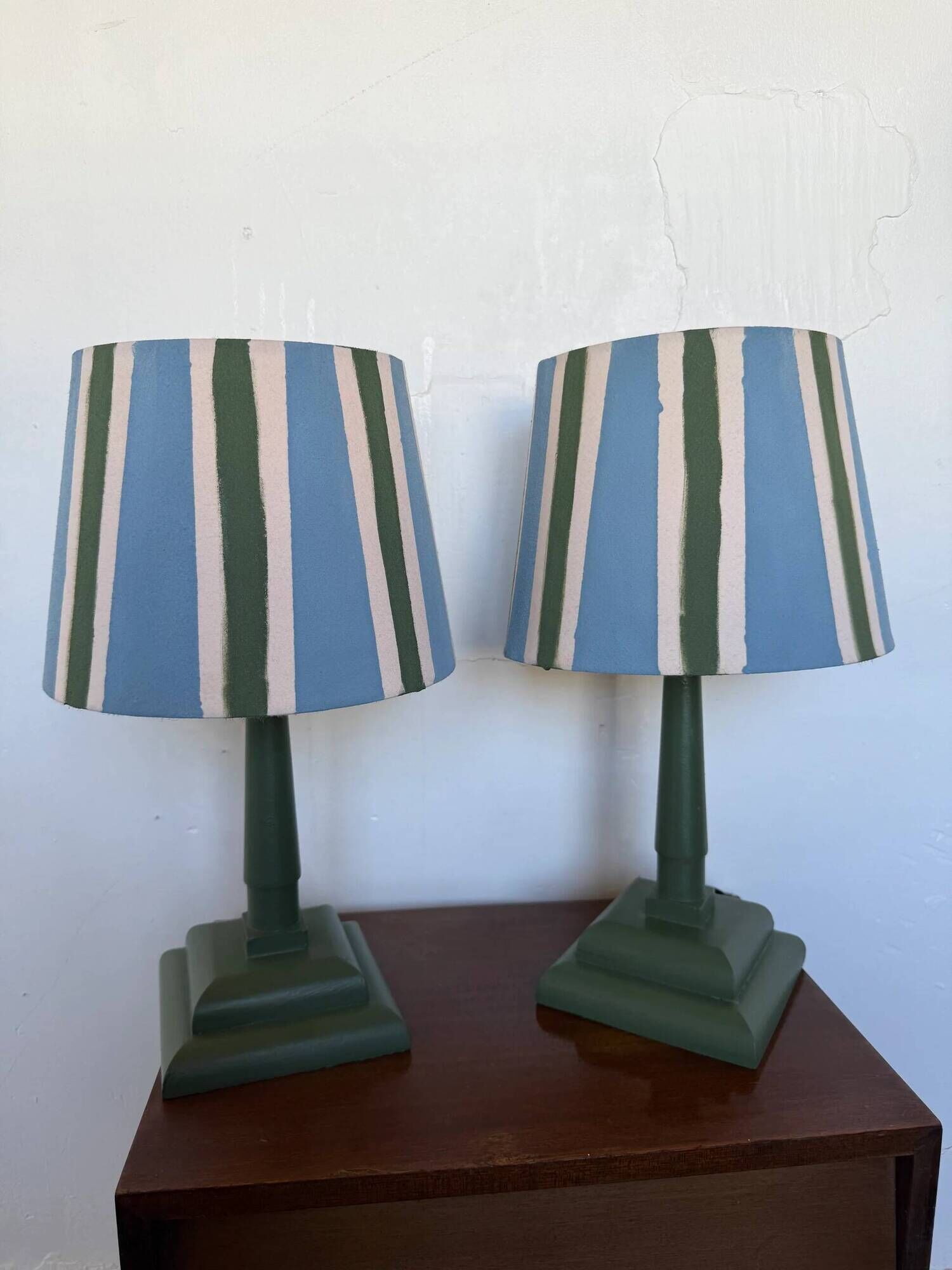 Pair of vintage wooden lamps with their striped beige, blue, and green shades.