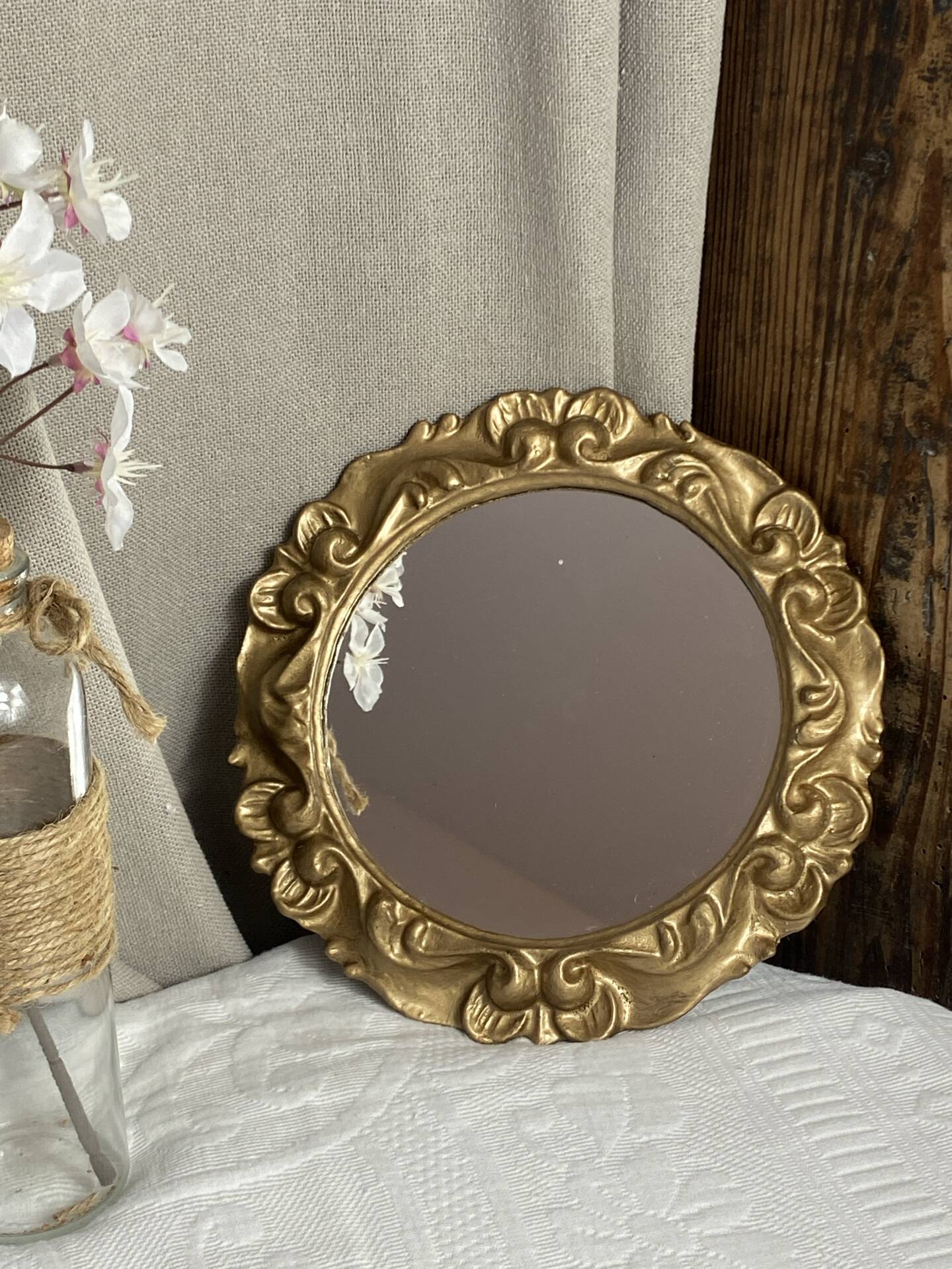 Round wooden mirror in golden colour.
