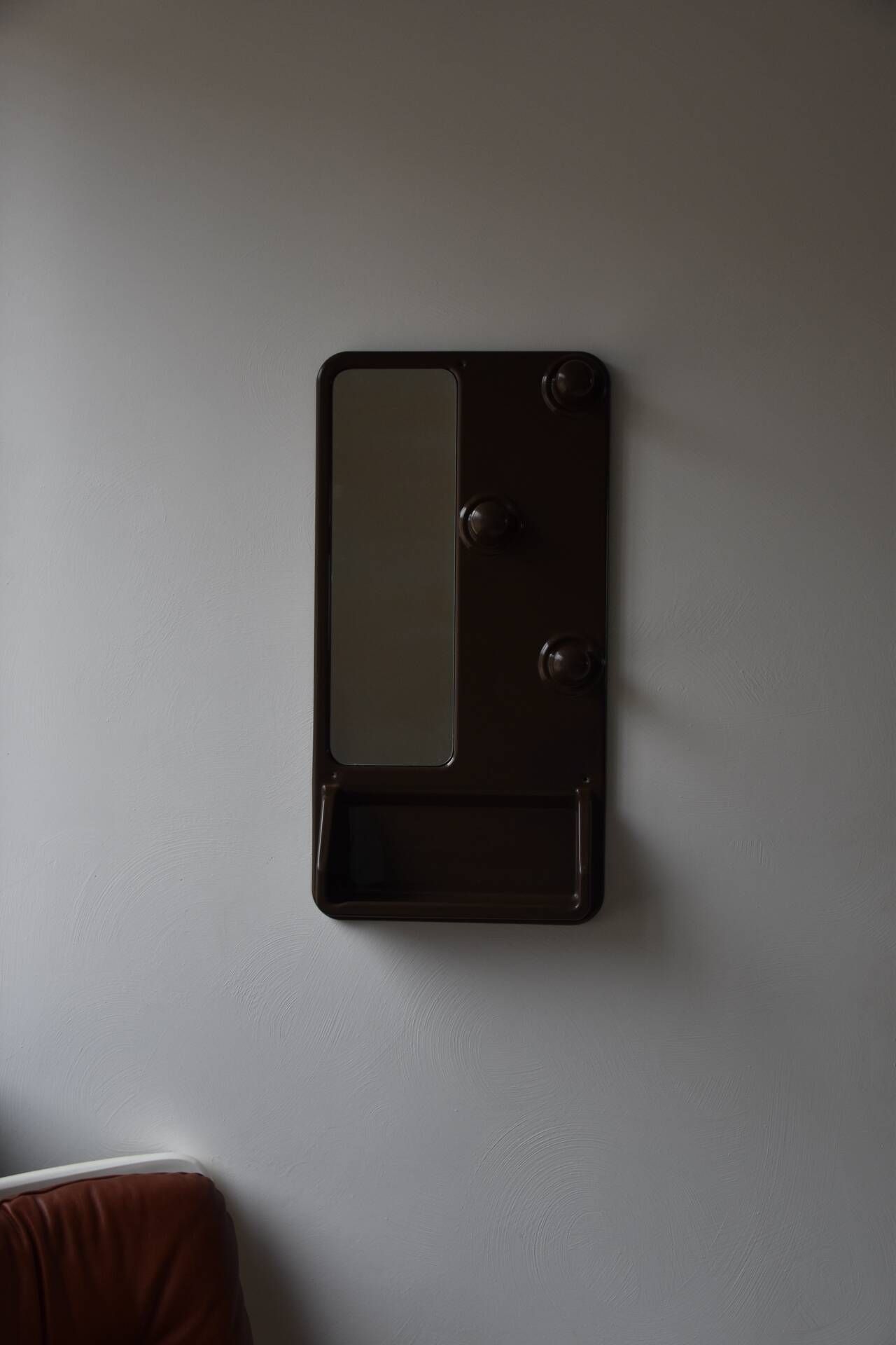 Wall mirror in moulded plastic with hooks and shelf.