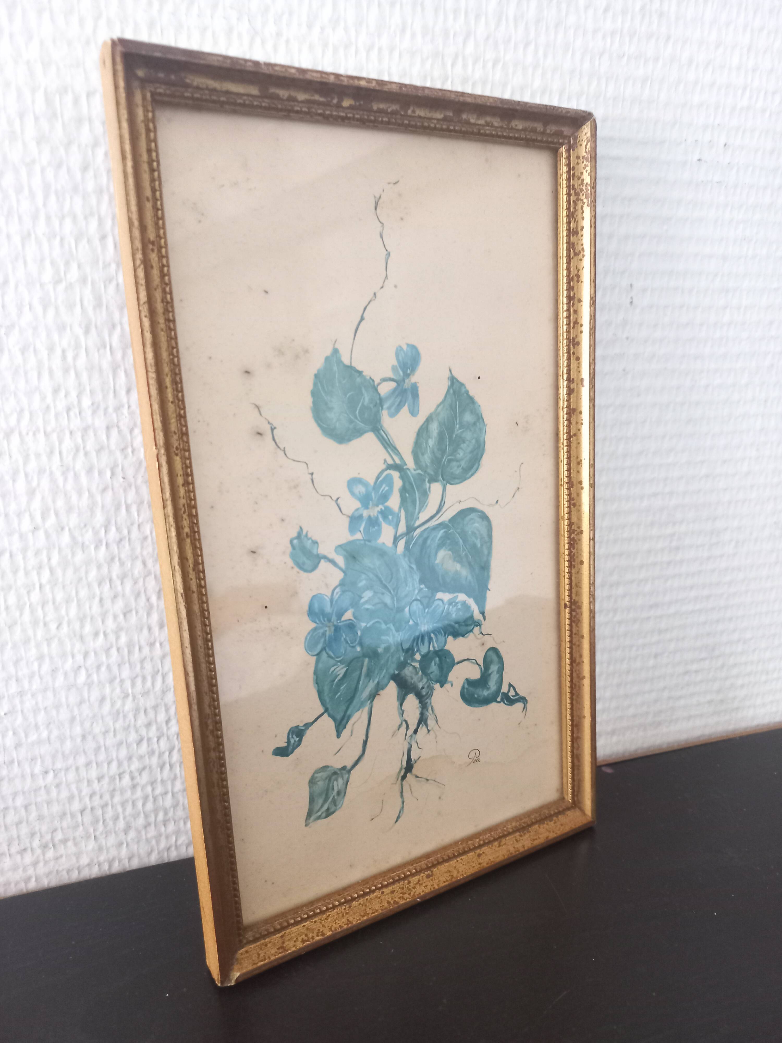 Decorative table with vintage blue flowers in a golden frame.
