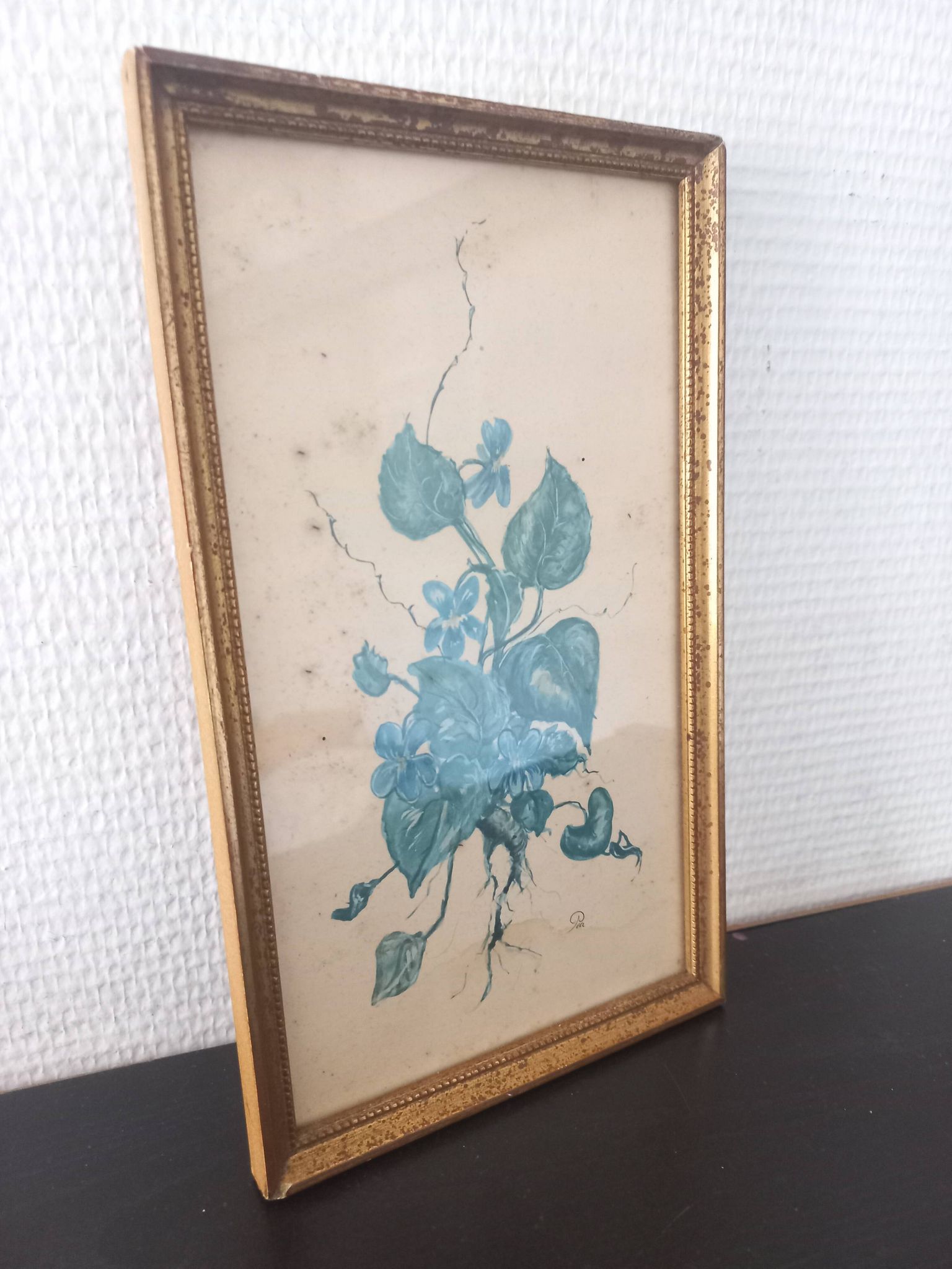 Decorative table with vintage blue flowers in a golden frame.