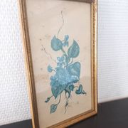 Decorative table with vintage blue flowers in a golden frame.