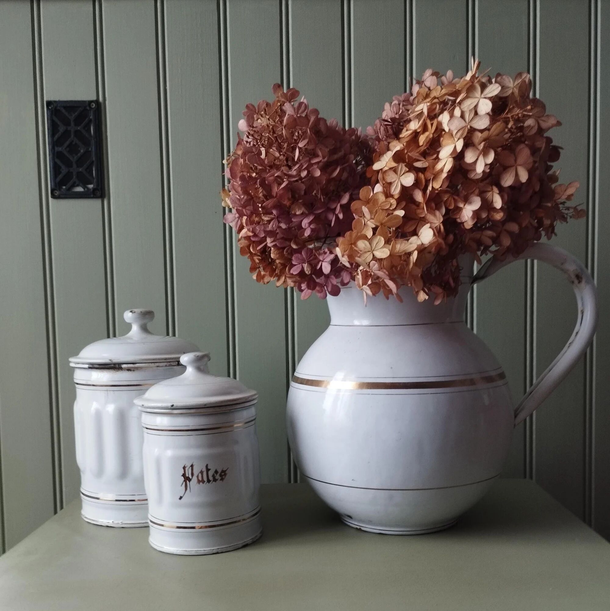 Old enamelled metal jug with gold trim.
