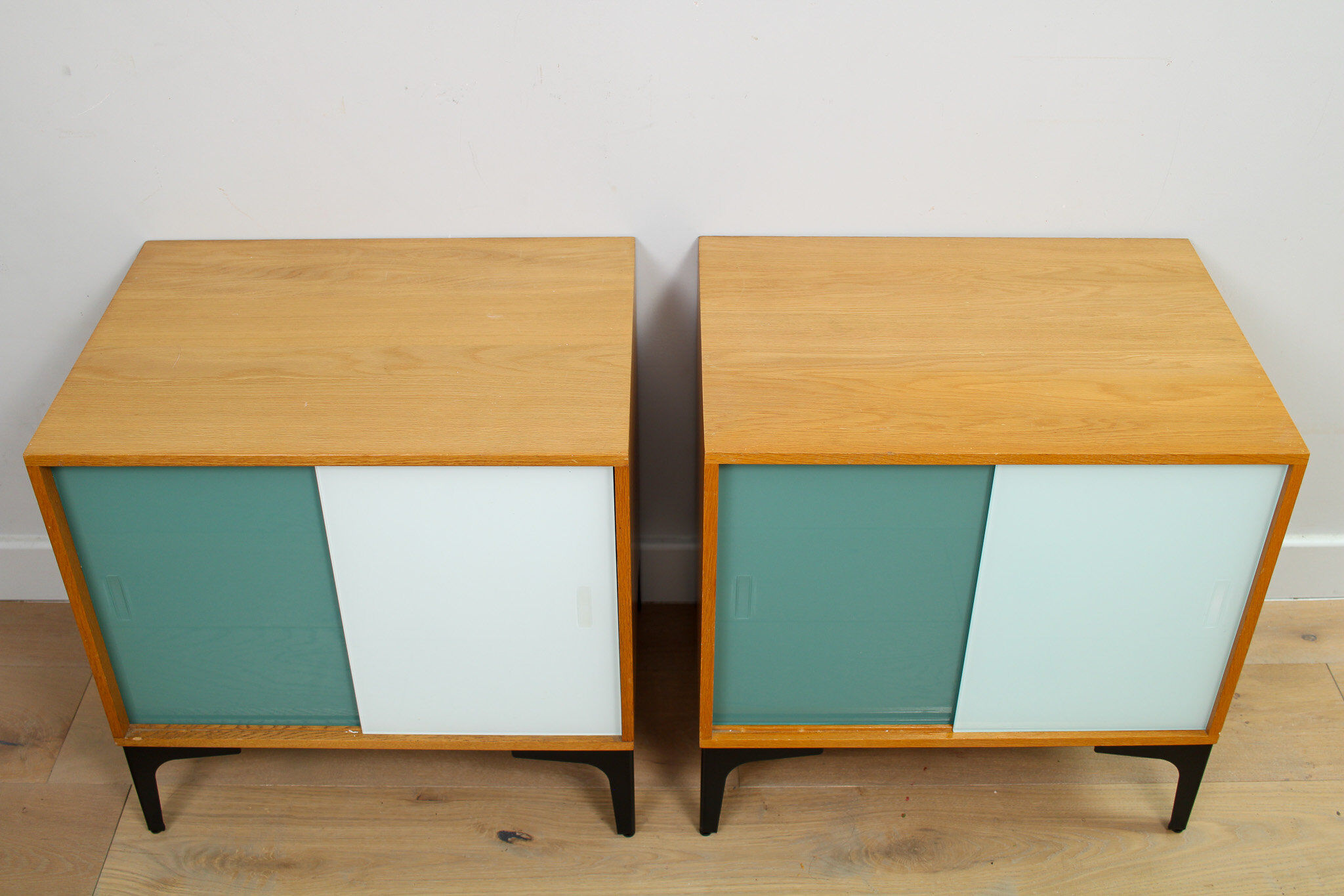 A pair of vintage mid-century bedside tables with glass sliding doors