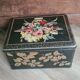 Old black metal box and flowers at the beginning of the century