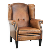 Grand et confortable fauteuil en cuir de mouton avec des passepoils noirs.