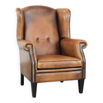 Grand et confortable fauteuil en cuir de mouton avec des passepoils noirs.