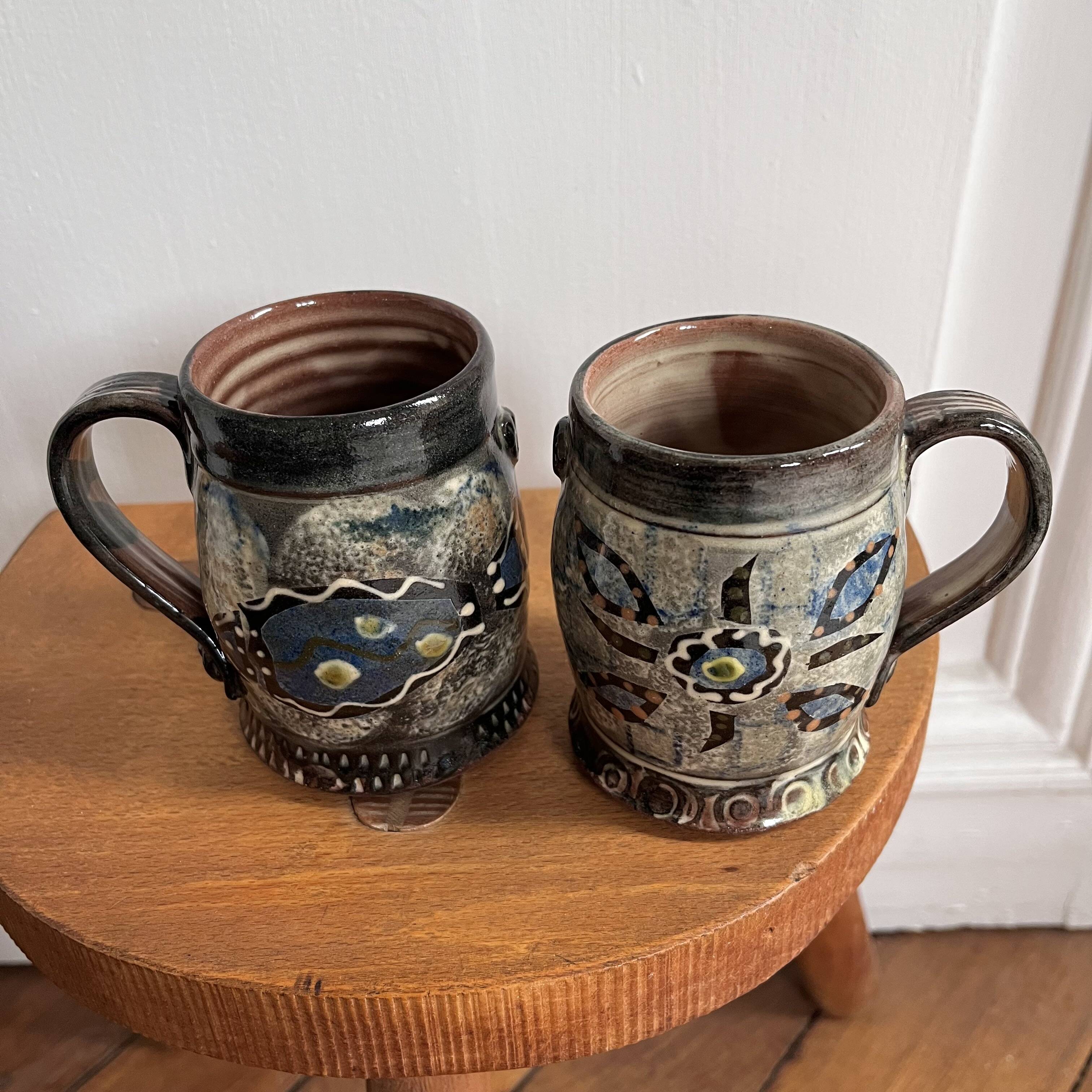 Vintage terracotta mugs with glazed designs and flower/fish motifs