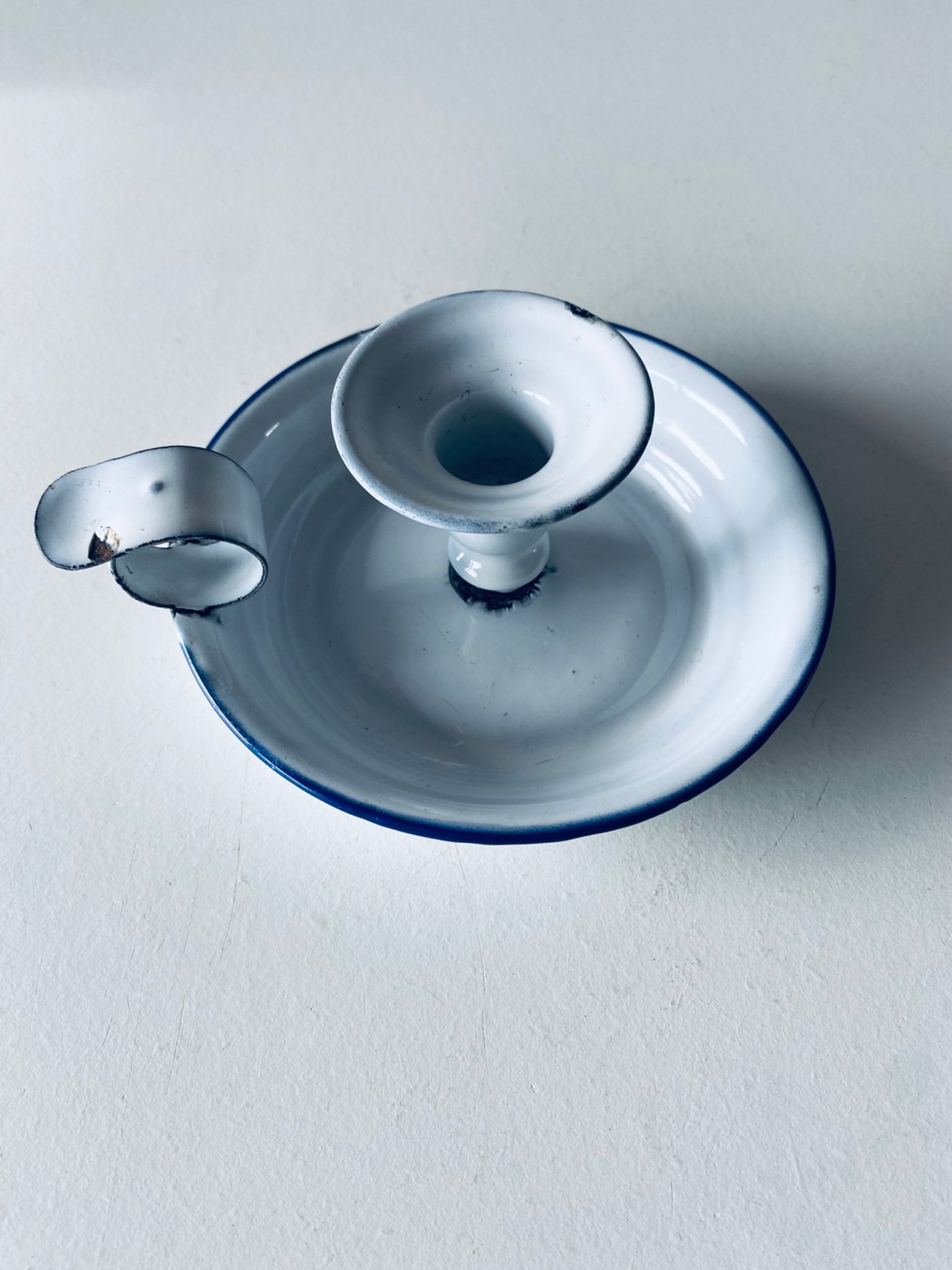 Old candle holder in white enameled metal