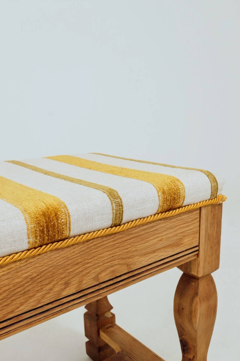 Vintage oak bench with striped linen fabric in a country style.